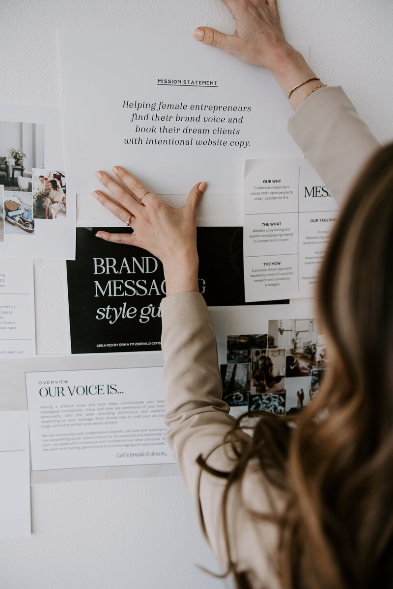 Erika Fitzgerald tapes website copywriting and brand messaging printouts to a whiteboard