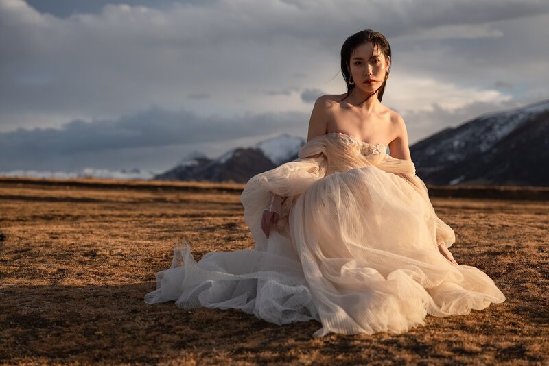 Couture dress bridal shoot on a field with mountains in the background and golden light.