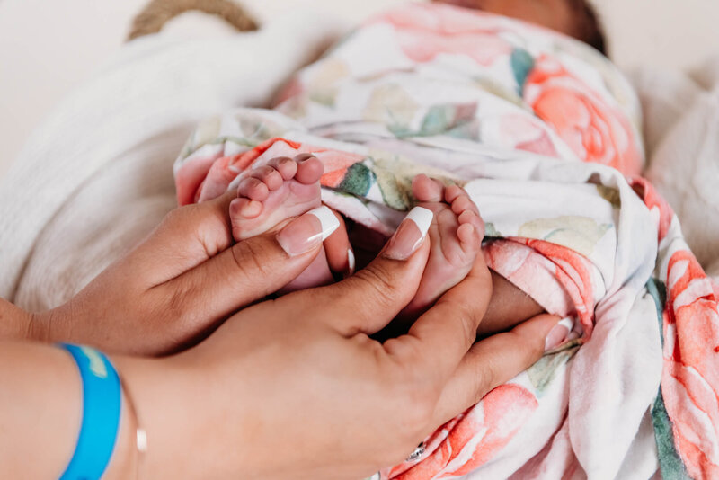Mother's hands holding her newborn baby's feet.  Photo taken by Delaware maternity photographer, Kristi