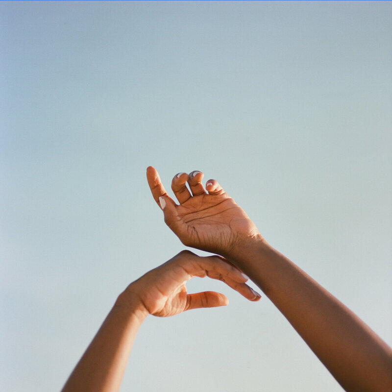 an image of black hands in the air on a website for motherhood coaching moms of color in Matrescence