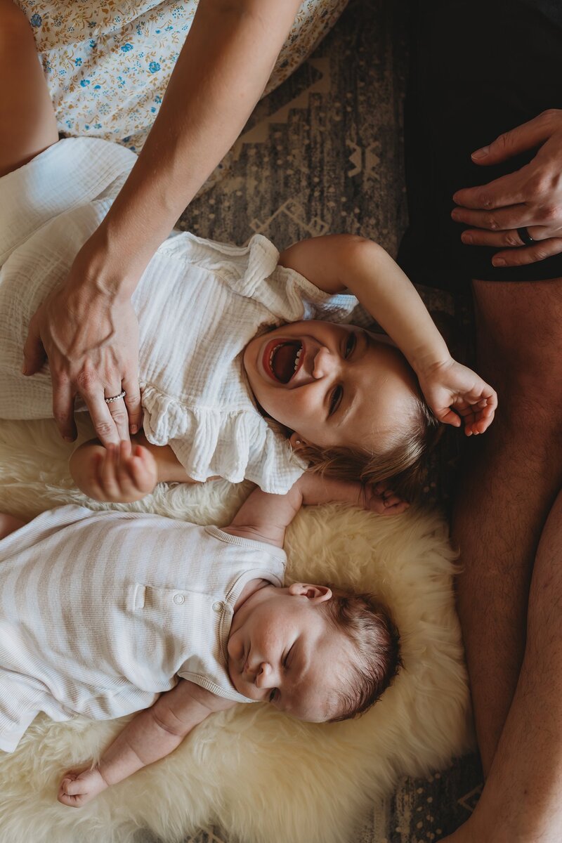 Newborn and little girl laying on the bed