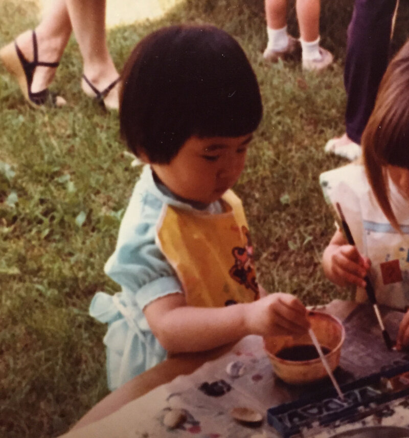Baby Saki (with a bowl hair cut) wearing a smock, plein air painting.