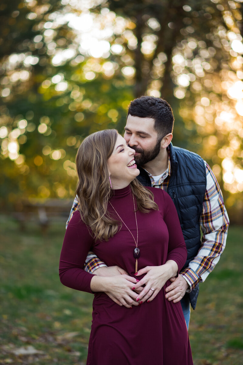 Happy couple embraces and kisses one another during their engagement session at a vineyard. Photographed by Aaron Aldhizer
