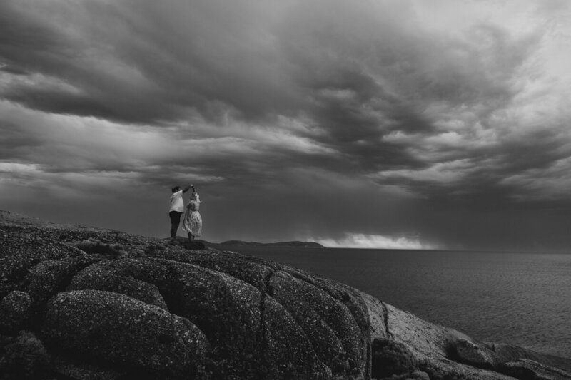 A black and white image of a couple at sunset during a thunderstom in Wilson Prom in australia.