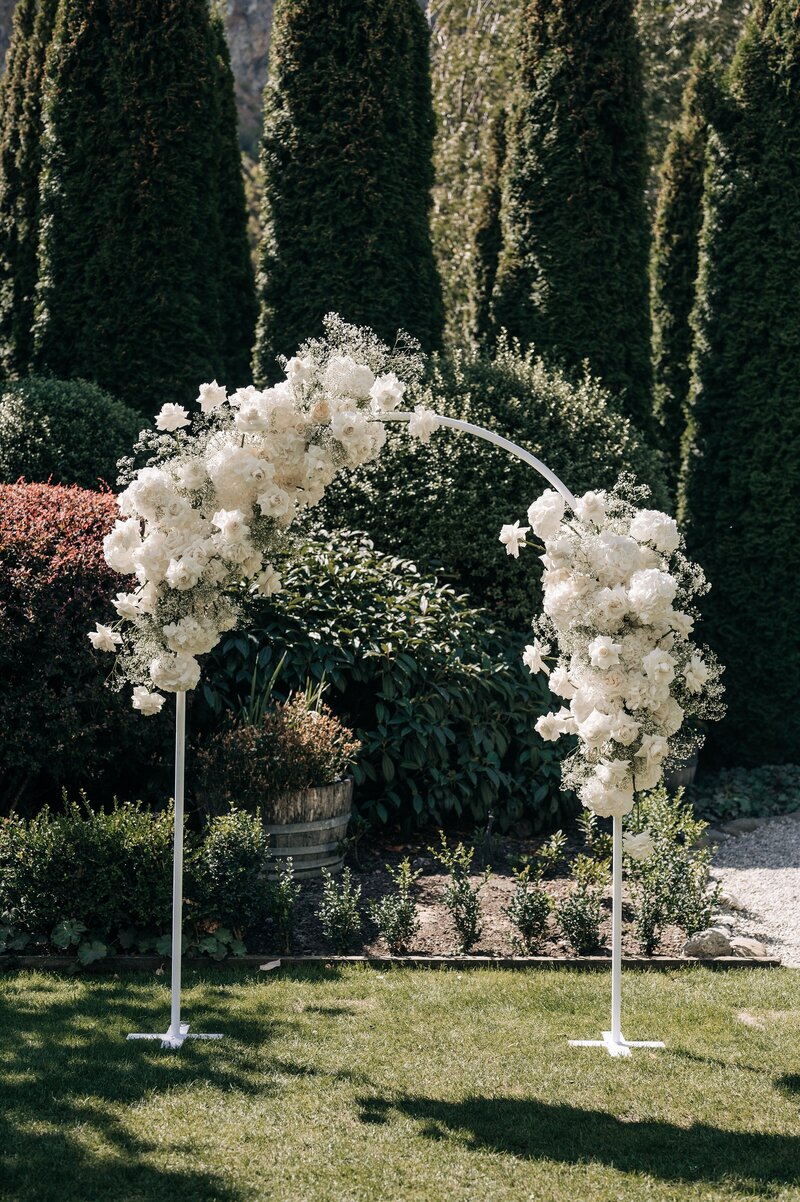 a white arch covered in white florals at the winehouse wedding venue in gibbston valley queenstown