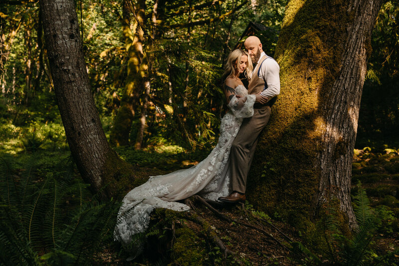 bride and groom leaning against tree
