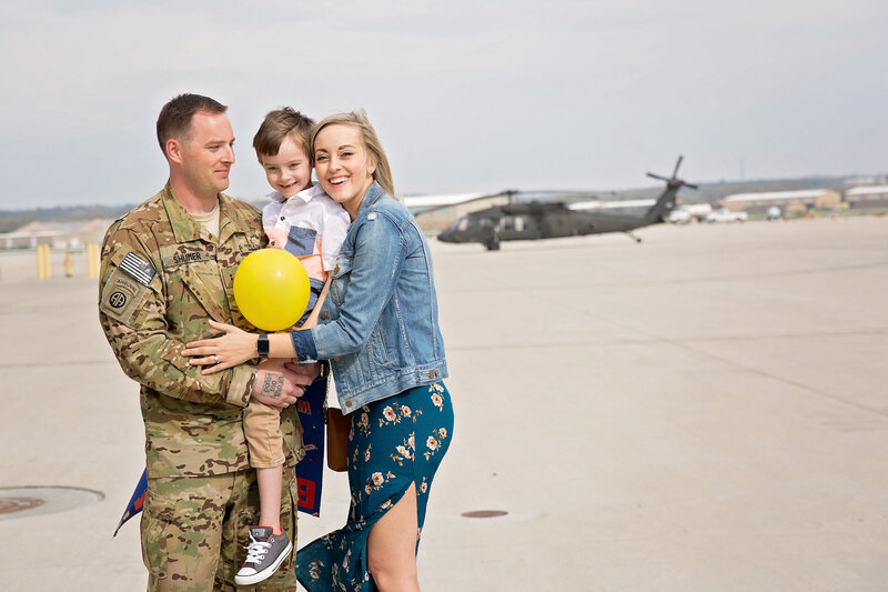 Military family poses in front of a helicopter during homecoming