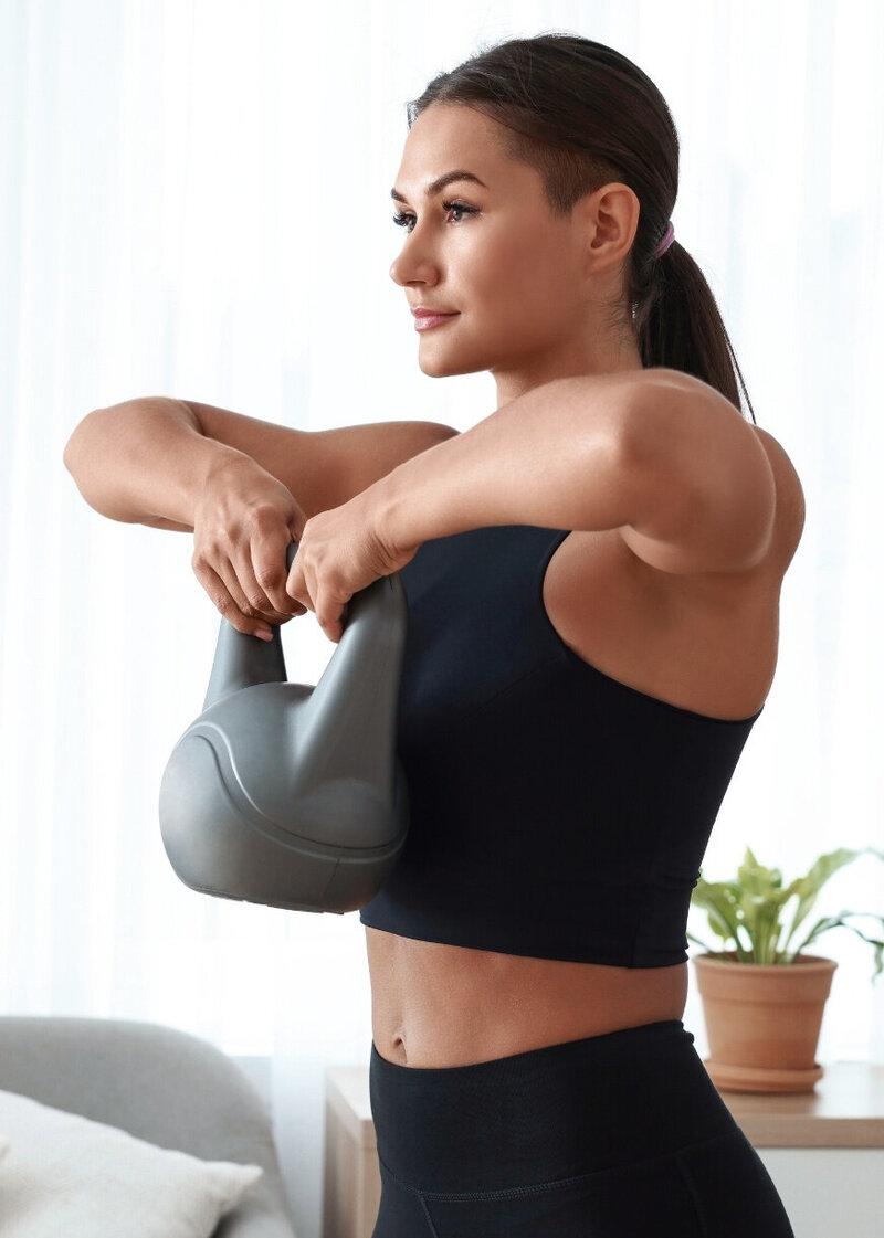 Midlife woman strength training at home with a kettlebell, part of the Rebells programme in the Menopause.Rescripted membership.