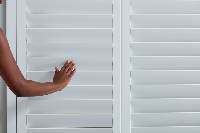 Woman's hand closing shutters on a window