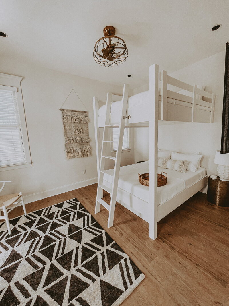 white bunk beds and black accent rug on wood floors