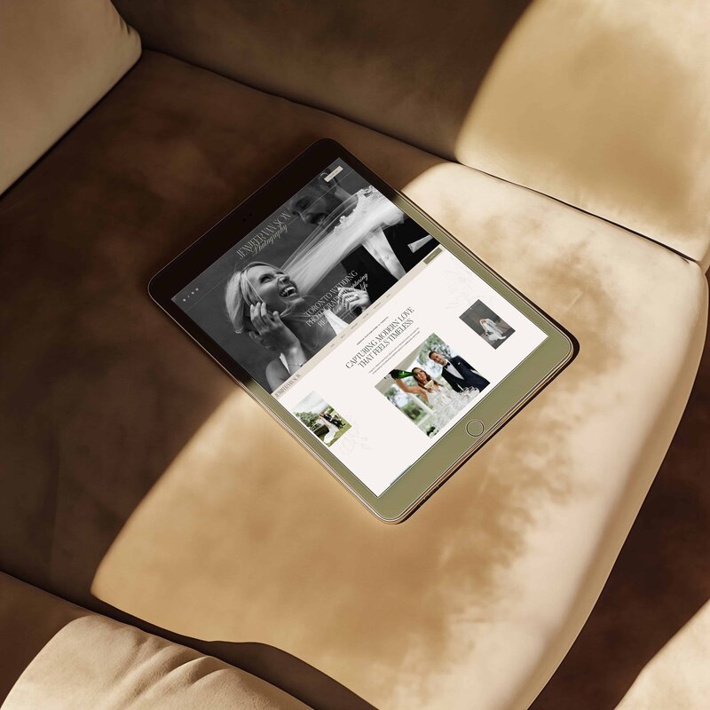 A tablet displaying custom branding and web design for a photographer with images of women in white dresses, placed on a light-colored textured surface—perfect inspiration for small business branding.