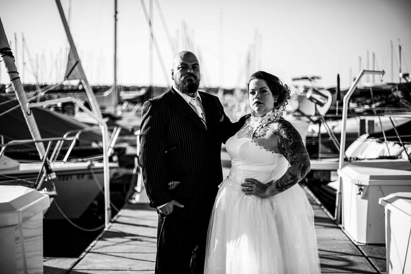 Bride and groom pose seriously among boats at the Erie Yacht Club