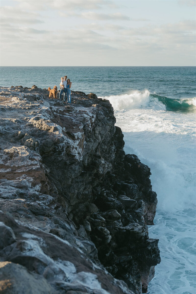 Wide landscape of a family styled in denim and neutrals on Maui cliffs, perfect for editorial family portraits.