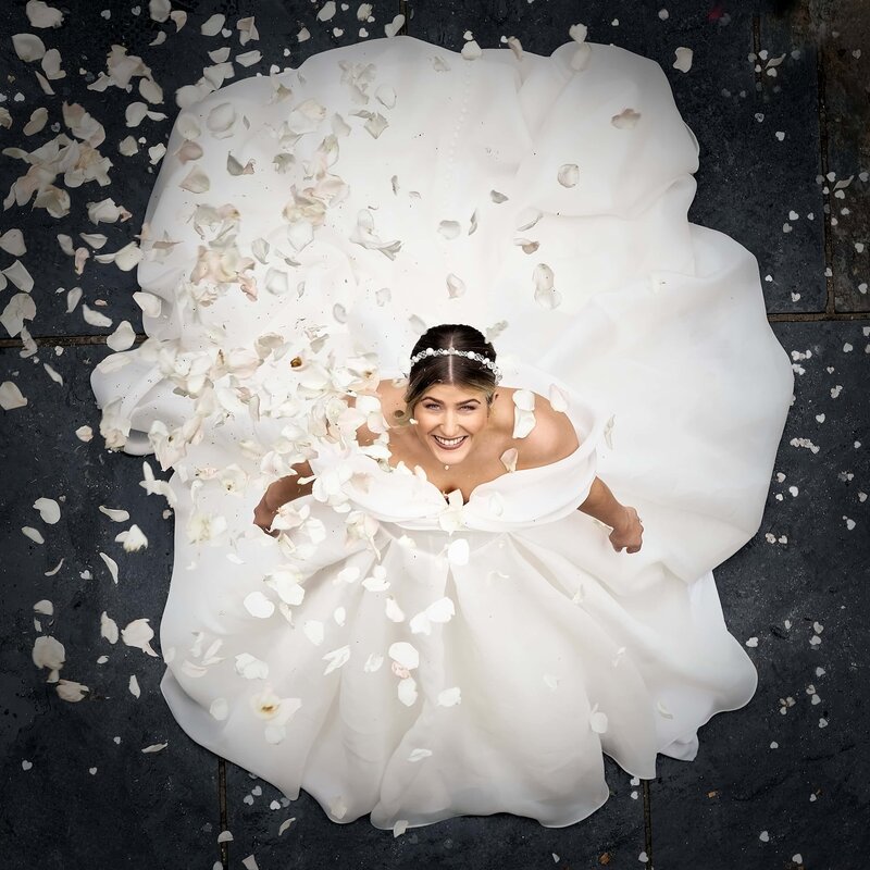 bride looking up at camera as confetti is thrown over her