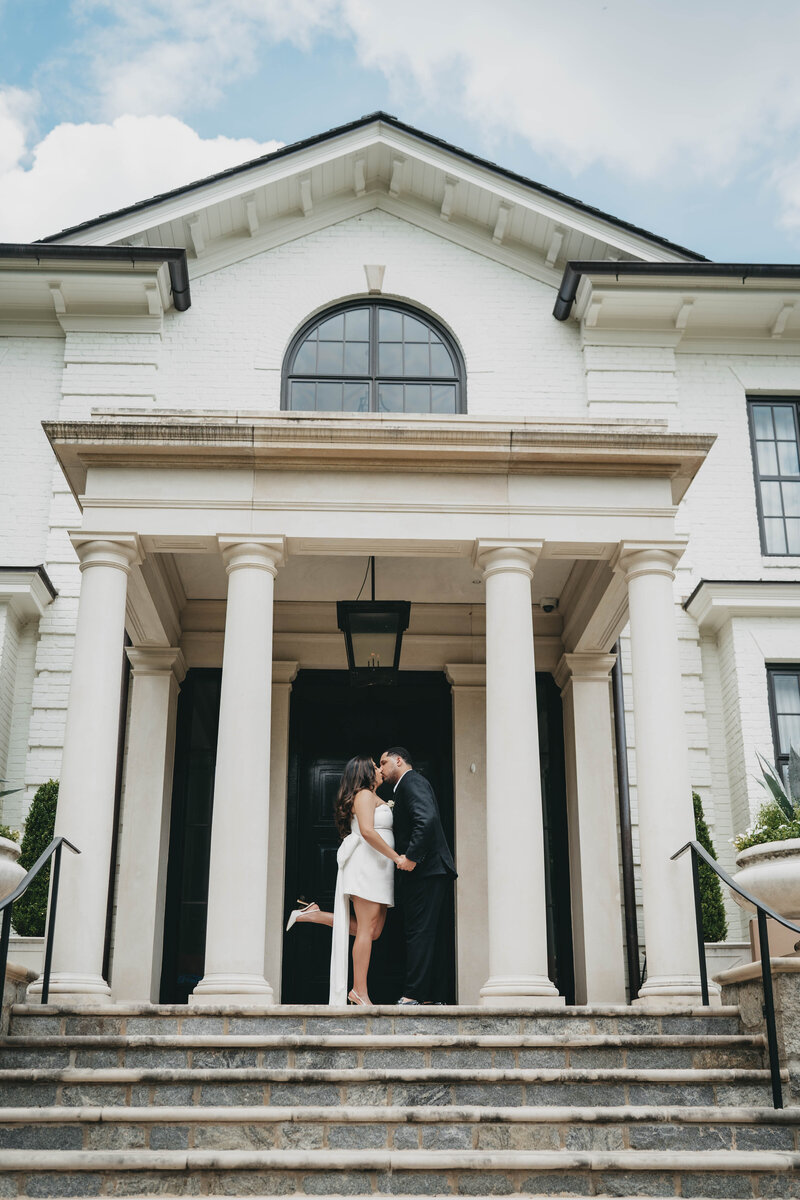 bride and groom standing in front of a courthouse kissing
