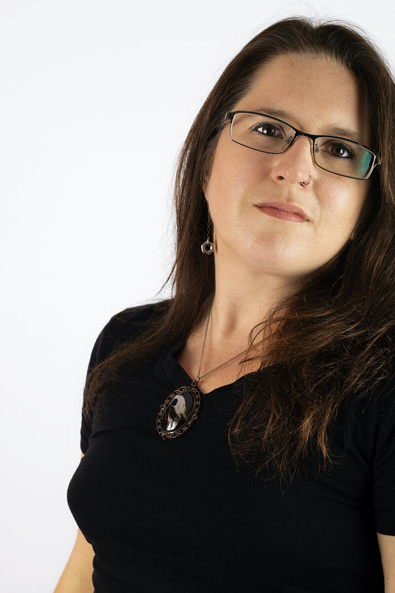 branding photo of a Philadelphia wedding photographer soft smiling at the camera. The framing is offset to the right, featuring the negative space behind her on the left of a white backdrop