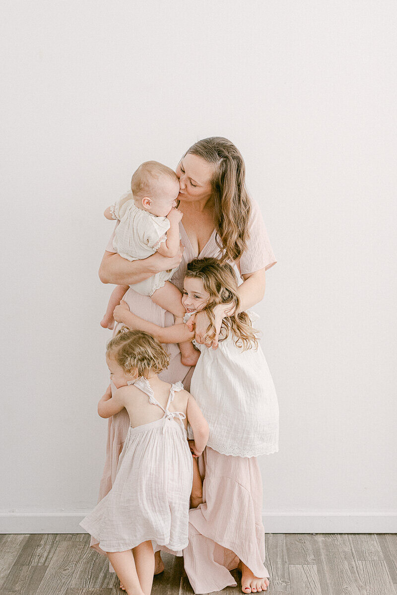 Mom of three girls  dressed in cotton flowy dresses for mommy and me photoshoot