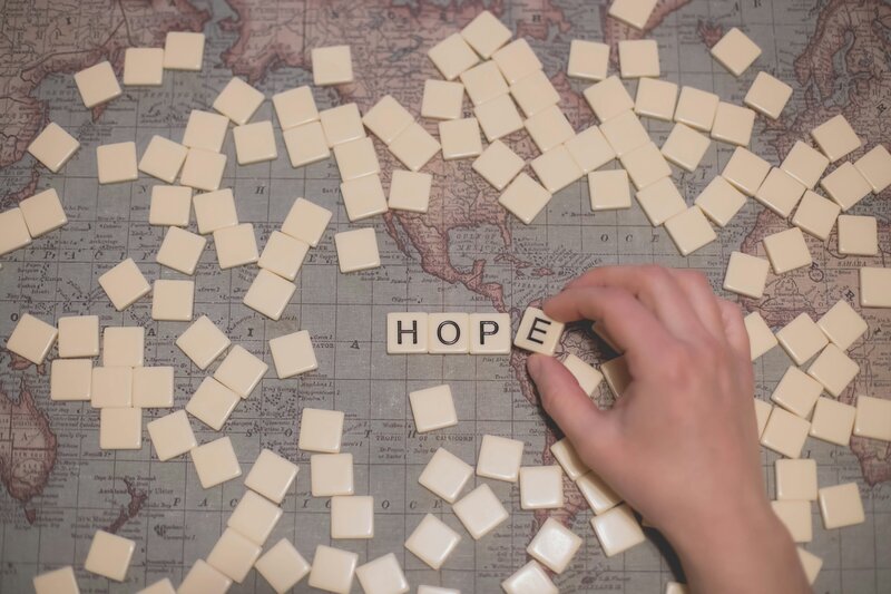 Image of a map with scrabble tiles, four are flipped over to spell HOPE.