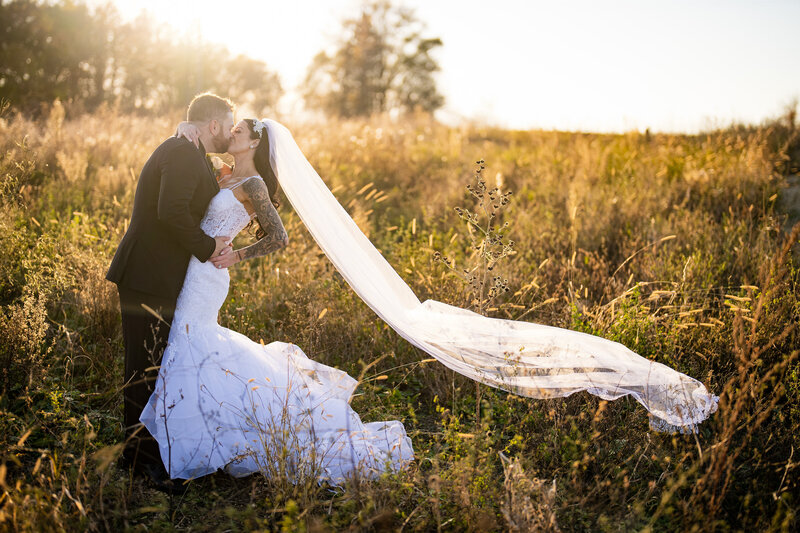 groom dips bride for a kiss in Wisconsin field at sunset