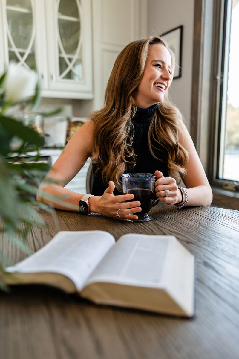 JaCee Petko, Christian life coach, sitting at a table with a coffee mug and an open Bible