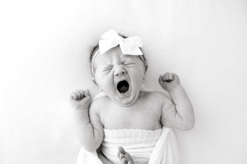 Black and white photo of newborn baby girl yawning