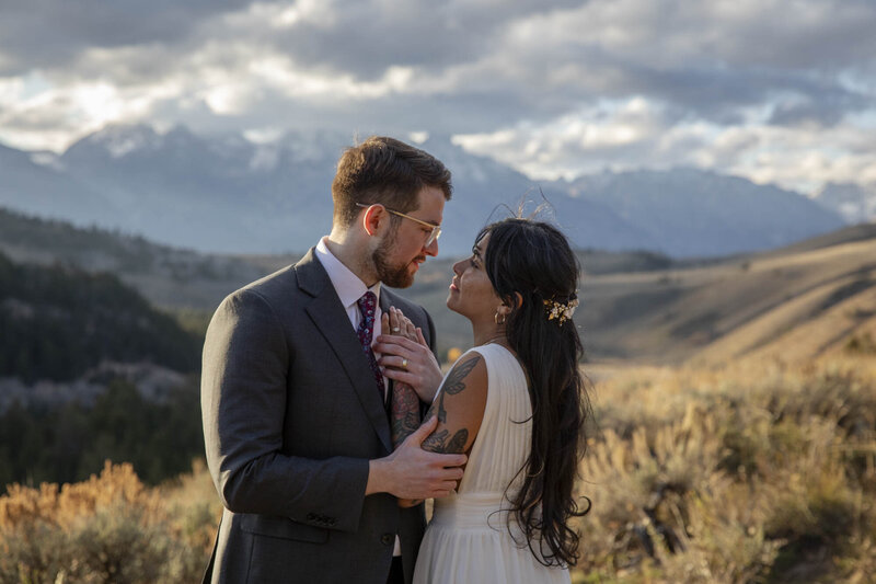 Couple embraces in golden light with a mountain backdrop during their intimate elopement