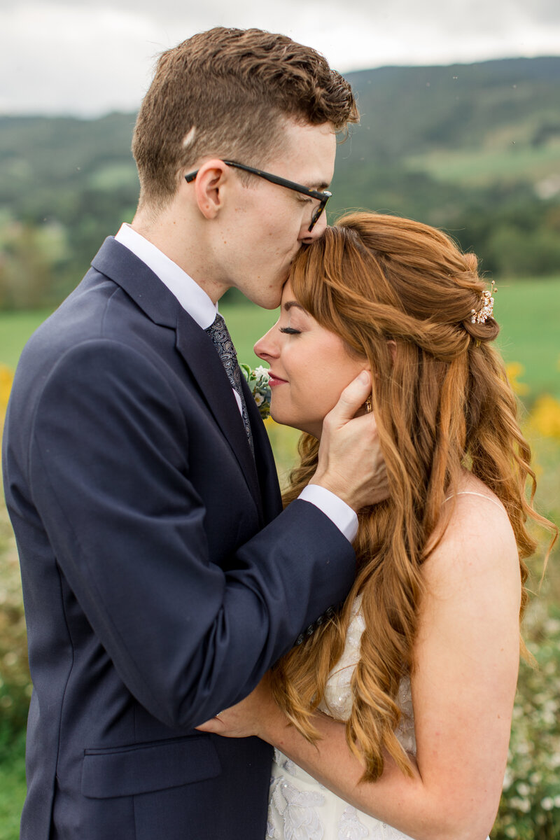 A wedding photo in Boone, NC of a bride and groom standing in a field in the blue ridge mountains.