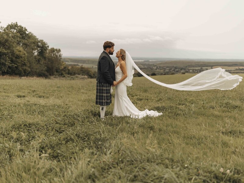 Bride and groom laughing in a field at sunset