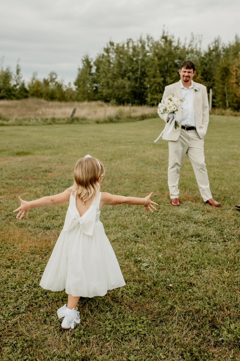 Groom's daughter runs to him with open arms during a large, traditional wedding in Minnesota.