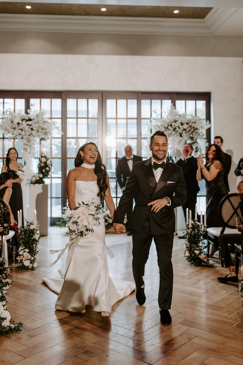 A couple smiles while walking down the aisle