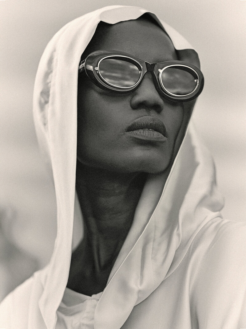 Close-up black and white shot of a woman wearing a white hoooded shirt wearing bold and stylish Matsuda sunglasses