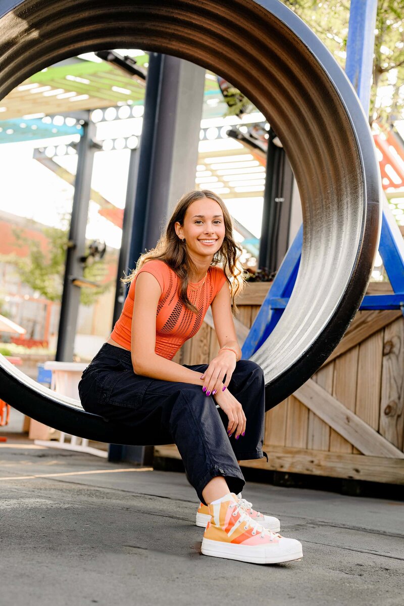 charlotte senior sits in big hoop wearing black pants and orange top
