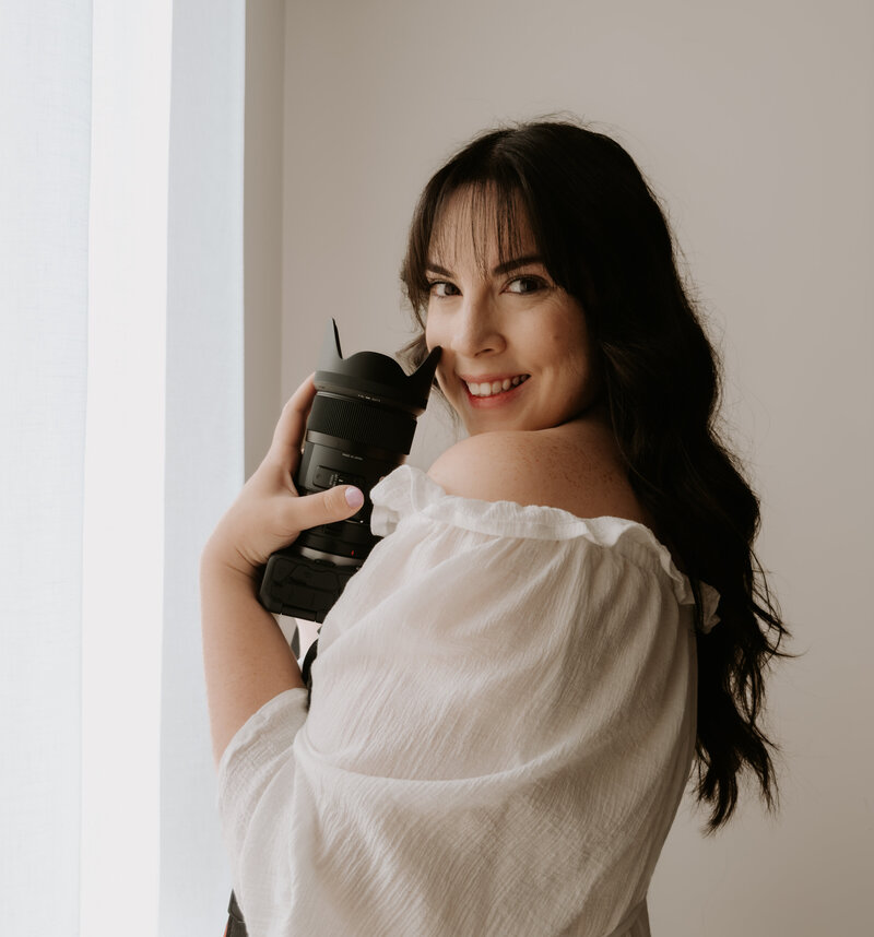 photographer holds camera near face while smiling