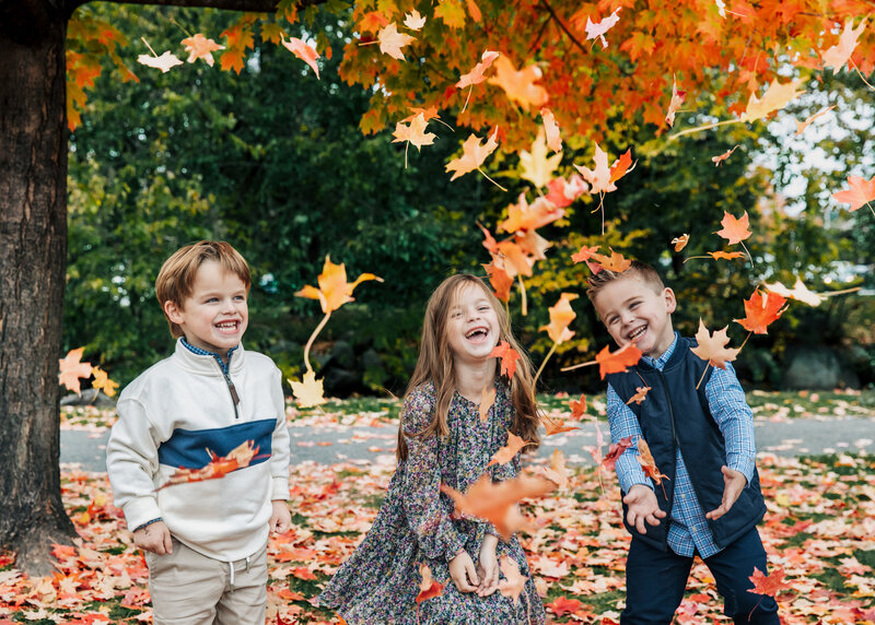 Siblings playing in fall leaves at an Essex County, NJ park.