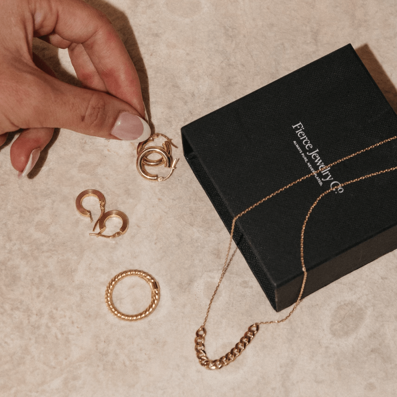 Fierce Jewelry Co 14k Gold jewelry in a black box with a finger holding the jewelry