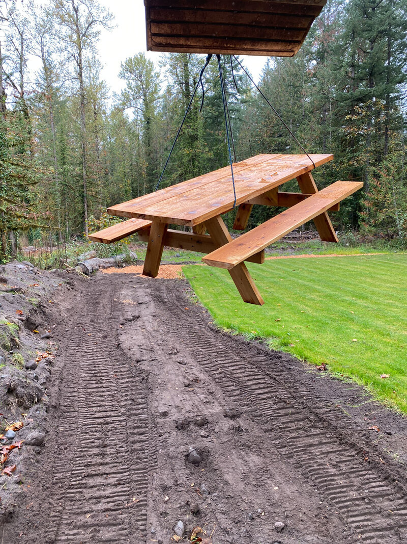 Wooden picnic table being lifted into place by equipment