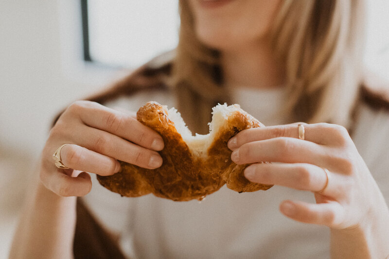 person tearing croissant