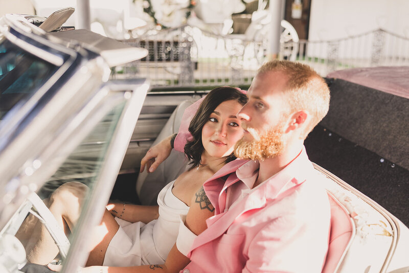 bride gazes at groom after elopement in classic car outside little white chapel in las vegas