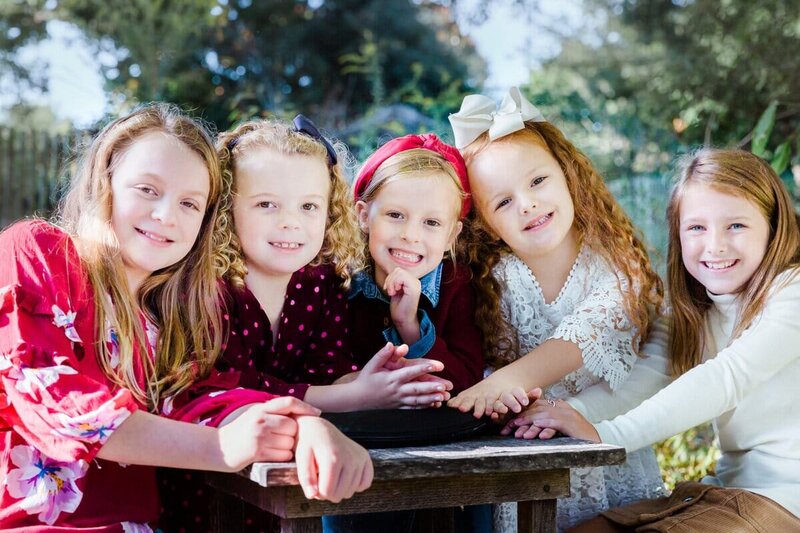 Family portraits of the five girl  cousins sitting at a table.