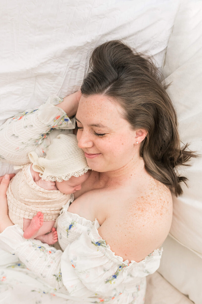 new mother snuggles newborn daughter laying down