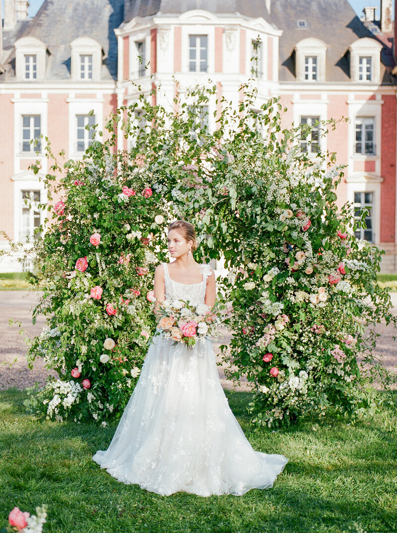 La mariée et son bouquet devant la magnifique arche florale