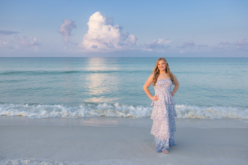 A girl standing at the water's edge with her hands on her hips