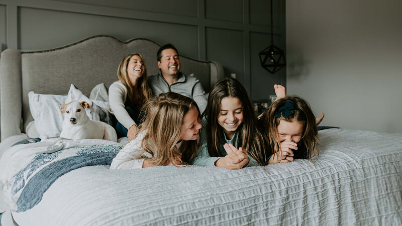 A Pittsburgh family photographer captured a family lounging on a bed with their dog in the background.
