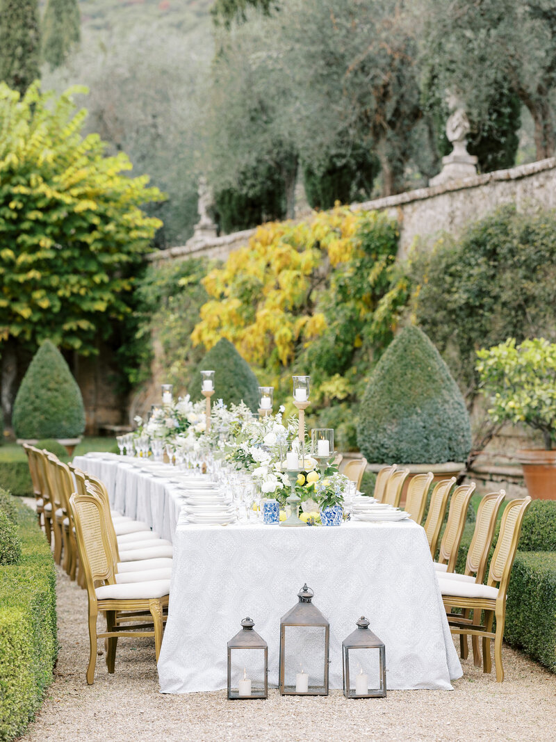 Curved table set in garden of Villa Cetinale in Tuscany, Italy with lemons, blue tile accents, place settings