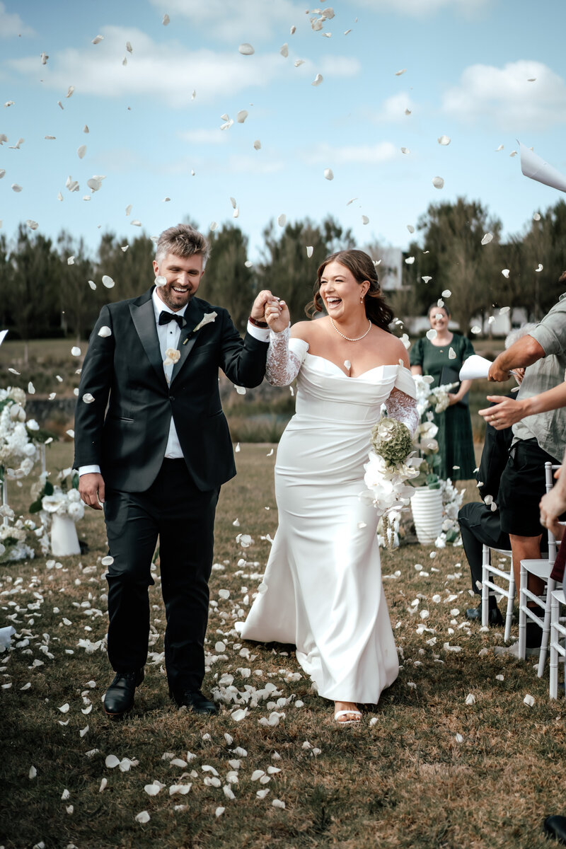 Bride and groom celebrating with confetti toss at outdoor wedding, romantic documentary photo by Auckland wedding photographer Zanthe Vorsatz.