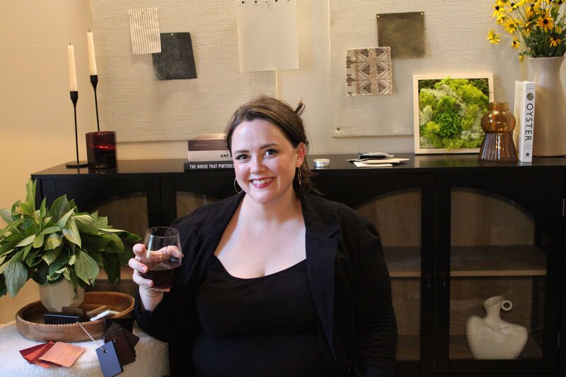Woman wearing black outfit holding glass smiling for camera