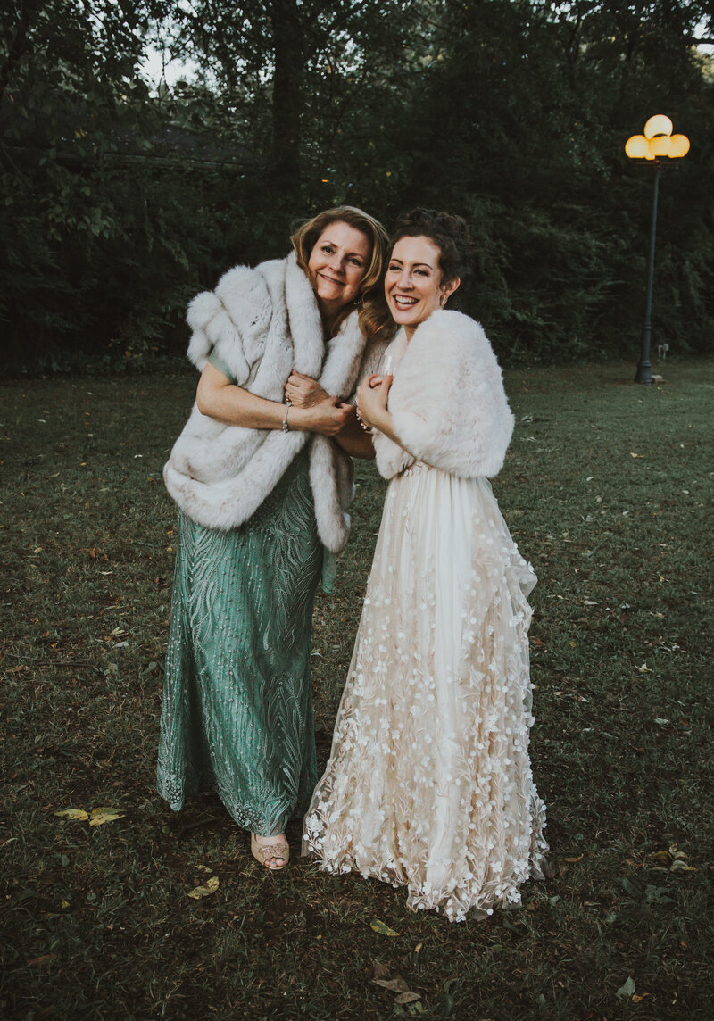 bride and her mother smiling outside in dark garden