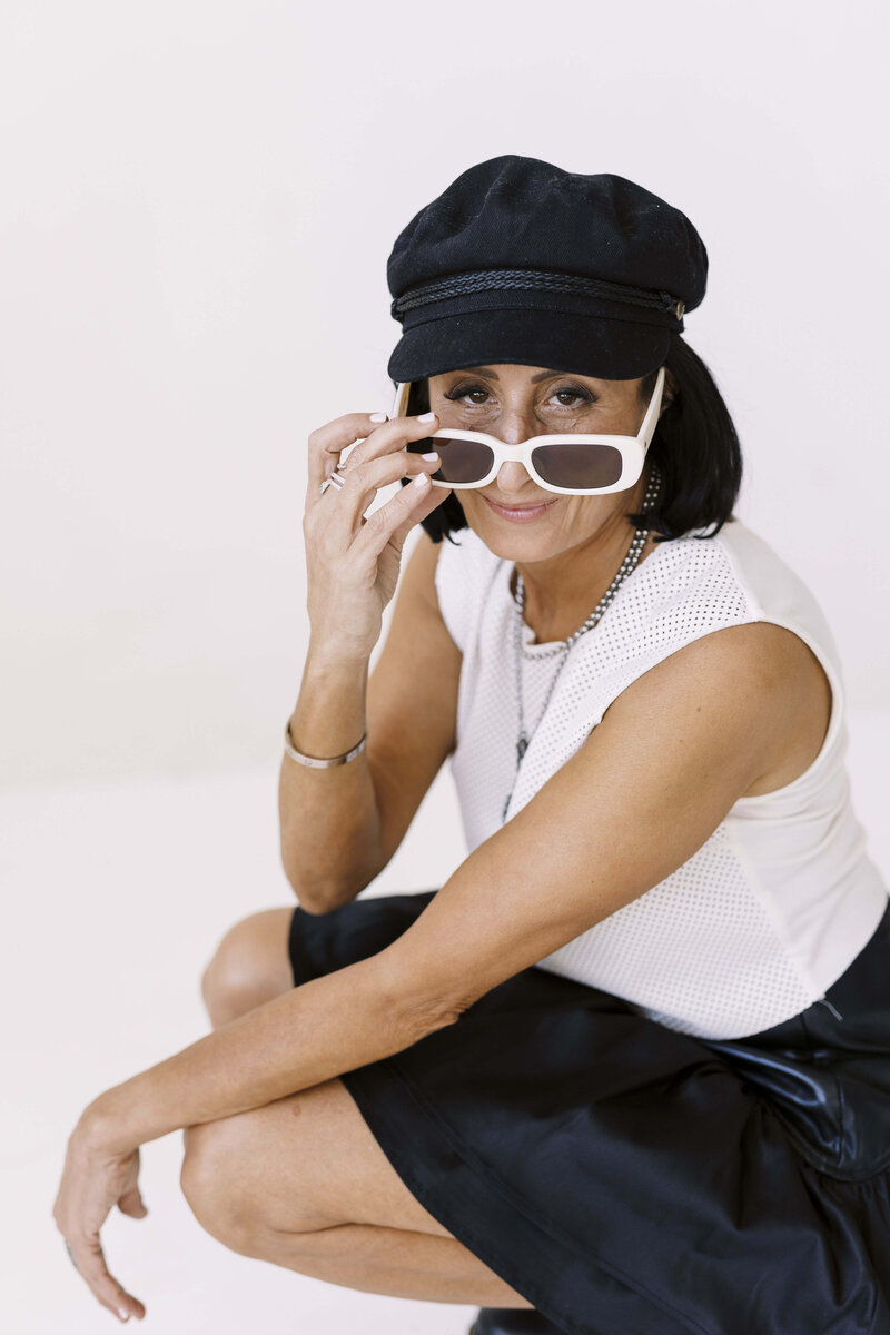 Tarah squating peeking over her sunglasses