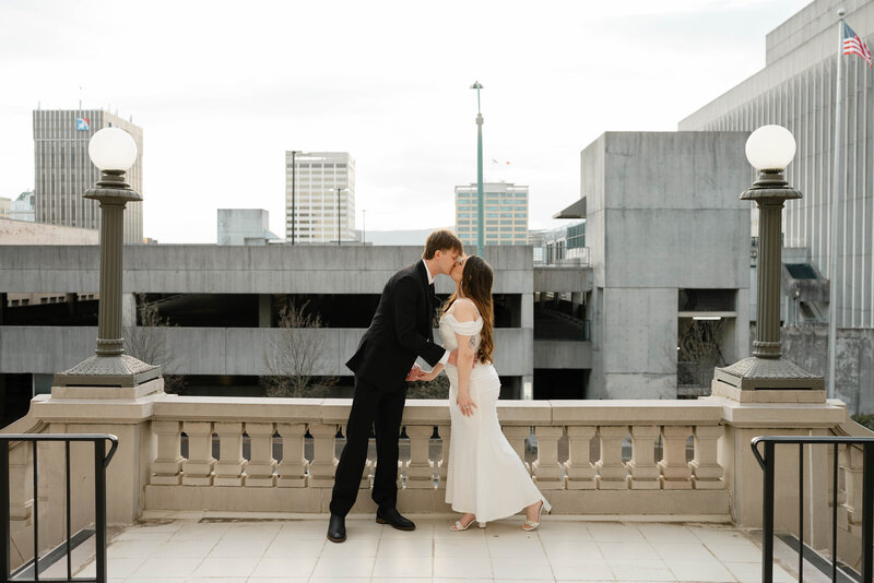 A bride and groom pose for a photo at sunset.