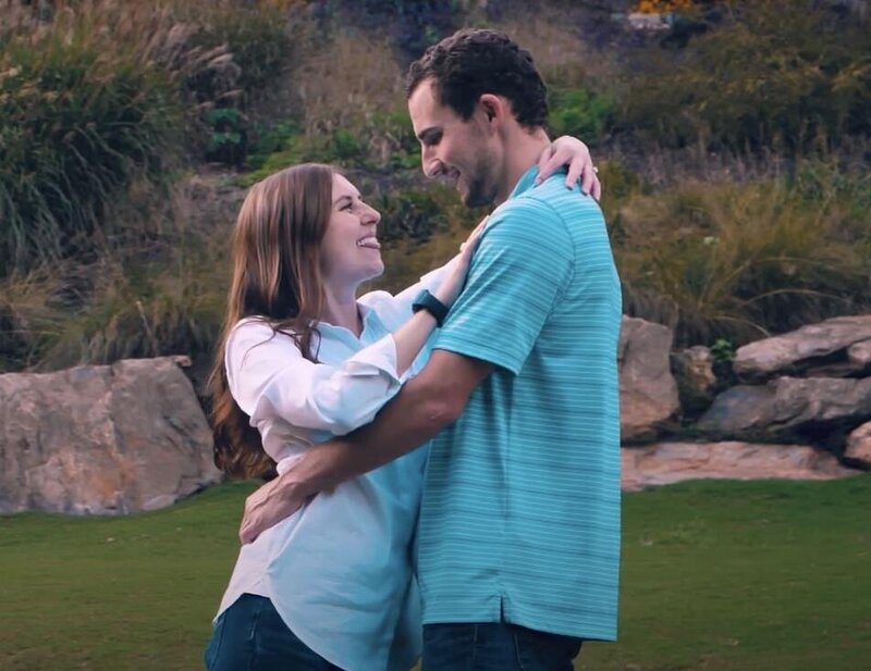 A couple laughing with their arms around each other 